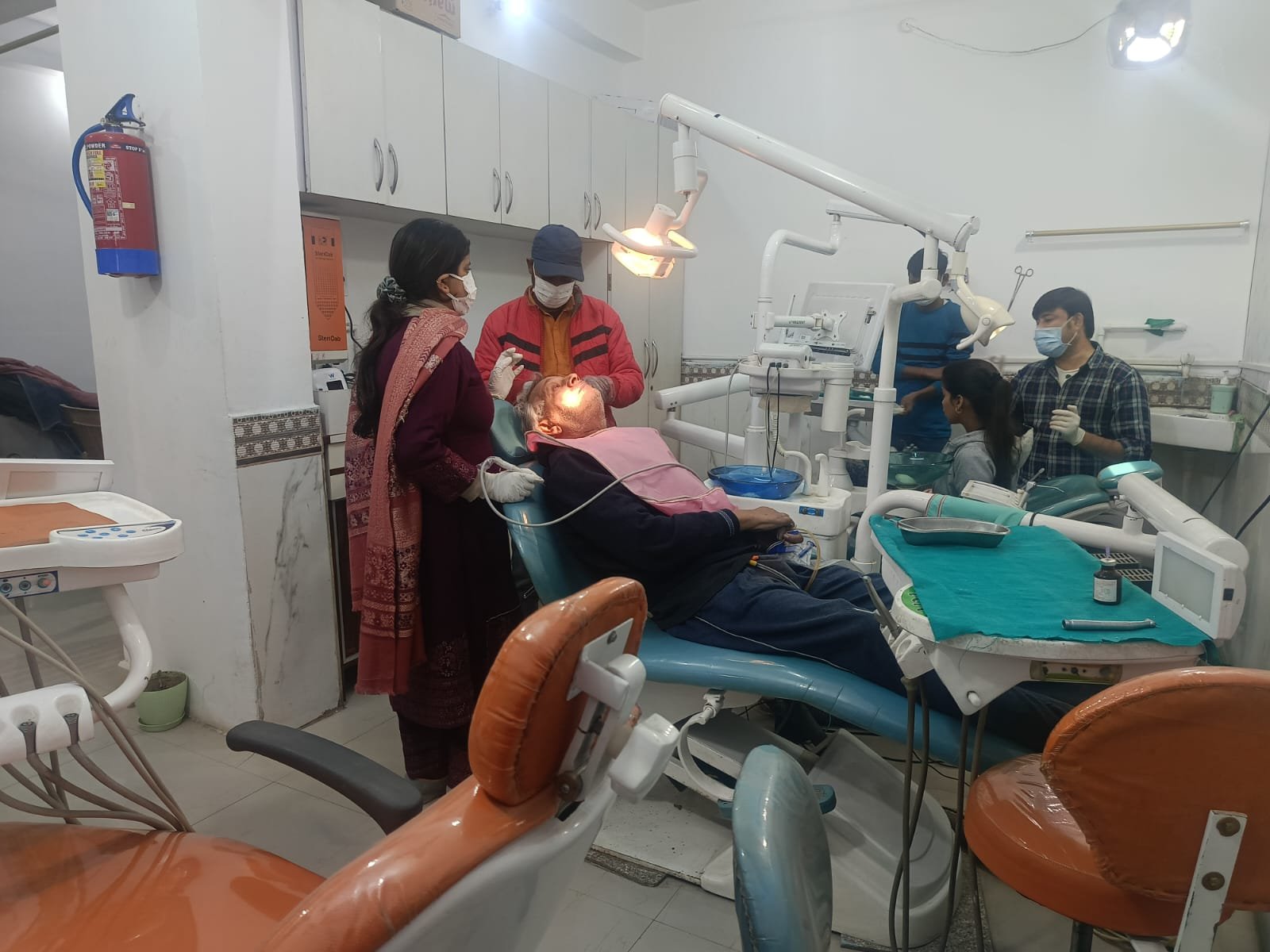 Full view of dental clinic with doctor and multiple staff attending to a patient
